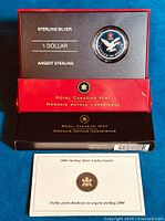 Single coin in presentation box alongside certificate, showing front display of packaging.