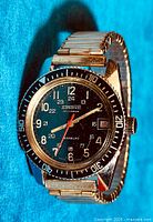 Front view showing black dial, bezel markings, red seconds hand and expansion band