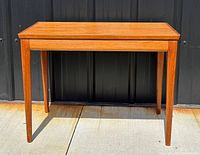 Front view of teak side table showing tapered legs and rectangular top in natural wood finish.