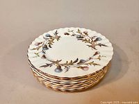 Stack of 8 Royal Albert Brigadoon bread and butter plates showing scalloped edges, floral thistle design, and gold gilded rim.