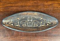 Top view of an oval elongated pottery dish showing detailed Haida Beaver design in engraved formline art style on the surface.