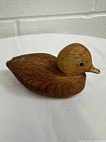 Hand carved wooden duck figurine showing detailed feather carving and profile.