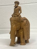 Front view of detailed wooden elephant with rider showcasing intricate carvings and the rider wearing a turban.