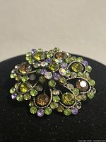 Front view of the vintage floral brooch showing multicolour rhinestones including green, purple, brown and clear stones.
