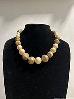 Front view of the beaded necklace on black display showing bead arrangement and color.