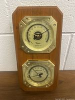 Front view of the Taylor barometer and temperature/hygrometer mounted on wooden board, showing both dials clearly with barometer on top and temperature/hygrometer below.