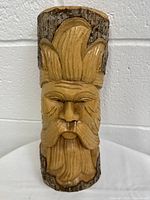 Front view of the hand-carved wooden green man statue showing detailed hair and facial features.