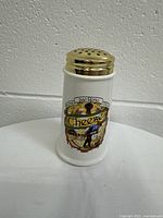 Front view of vintage porcelain cheese shaker with decorative Buona San Remo Italia label and gold-tone lid.