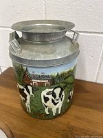 Front view of the vintage metal bucket showing painted cows and barn scene.