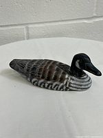 Front and side view of hand carved and painted wooden duck decoy depicting realistic feather details and color.