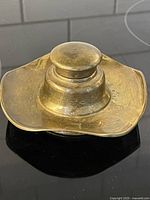 Top view of brass inkwell showing ruffled square base and lid