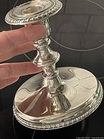 Side view of one candlestick showing base, stem and gadroon rim