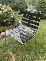 Front angle of black slatted Parri chair on lawn