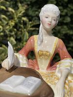 Front close-up of figurine showing face, upper body, quill and book