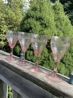 Four pink etched wine glasses lined on railing