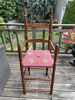 Front view of tall hardwood chair with floral needlepoint seat