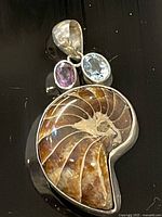 Front view of sterling pendant showing fossil ammonite, amethyst, blue topaz