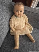 Full view of doll seated on sofa showing overall appearance and dress