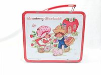 Front view of the lunch box showing main Strawberry Shortcake illustration with red border and handle.
