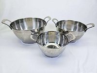 Set of three stainless steel colanders arranged showing the front and open top, placed on a white surface.