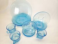 Photo showing the set of azure blue glass plates, bowls and cups arranged to display scalloped edges and ribbed texture