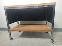 Front view of MCM rolling table/cart showing wood top and lower wood shelf with metal frame and caster wheels.