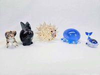 Photo showing all five animal figurines lined up including a brown squirrel, black rabbit, clear spiky hedgehog, blue octopus, and blue whale on a white background.