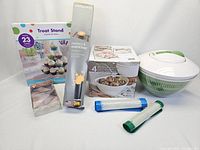 Full view of all items in the set showing the treat stand, pastry cutters, oven liner, serving bowls boxed set, salad spinner, and baking mats.