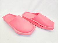 Side and angled view of coral pink Nike Hex slides showing the sleek modern design and hex-shaped sole edges.