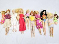 Overview of 10 vintage Barbie dolls with various outfits laid flat on white background