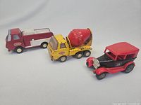 Photo showing the three Tonka trucks from a side angle, displaying the tanker, cement mixer, and vintage style car.