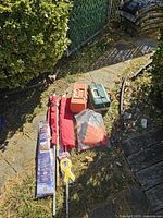 Overview of two fishing tackle boxes, two collapsible cases likely for fishing rods or flags, a yellow ribbon flag on a pole, and a red/orange flag inside a transparent carrying bag.