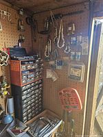 Overview of metal storage cabinet with multiple small drawers on pegboard, assorted hand tools hanging around