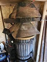 Full view of the old wooden wine press showing wooden staves and mechanical parts on the top section.