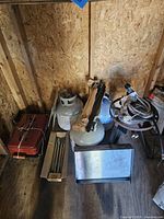 Wide view of propane tanks, grill parts, and outdoor burner in shed.