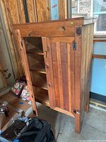 Side angle showing wooden armoire with left door open revealing shelves