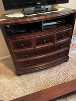 Front view of wooden chest of drawers / TV unit with TV on top.