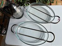 View of two oval clear glass serving trays with metal handles placed side by side, and electric kettle on the table; shows item condition and materials.