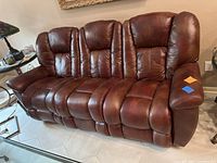Front view of brown leather reclining sofa showing three seats with padded cushions and armrests.