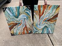 Pair of two matching abstract art photos held by person, showing front designs and protective corners.