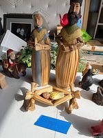Full nativity scene with Mary, Joseph standing, and Baby Jesus in a straw manger on a table with other decorations.