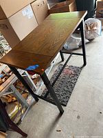 Side-angle view showing the wooden tabletop, iron legs, and support bar beneath.