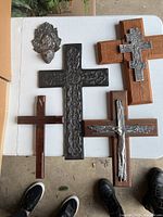 Five unique crosses laid flat on a white surface showing wood and metal details.