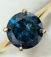 Close-up top view of round brilliant cut blue diamond in four-prong setting