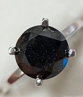 Close-up of the top view showing round black diamond and prong setting