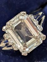 Front view of ring showing emerald-cut center stone and side diamond accents