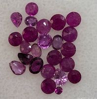 Close-up photo of multiple loose genuine rubies in various shapes and sizes on a white background.