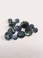 Loose genuine sapphire gemstones displayed on a white background showing different angles and cuts.