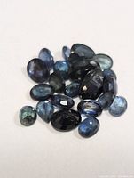 Collection of assorted genuine sapphire gemstones shown from above on a white background.