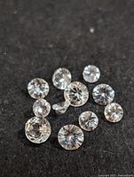 Multiple loose round cut gemstones on black background revealing facets and clarity.